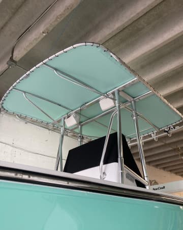 Mint green bimini top on a seafoam center console boat in a covered slip