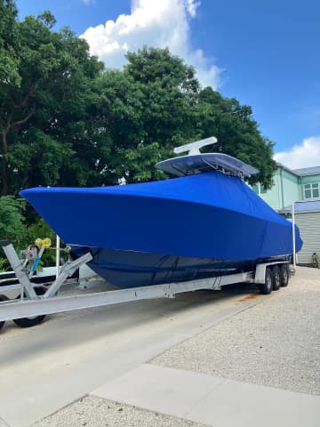 Royal blue full-boat cover fitted over a center console on a trailer