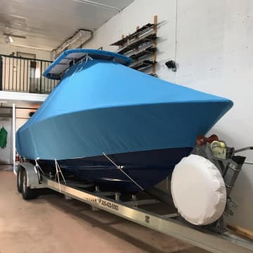 Blue fitted boat cover on a trailered center console inside the shop