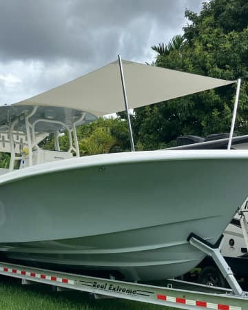 Cream shade sail extended over the bow of a green center console boat